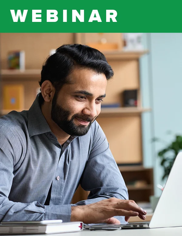 A bearded man smiling while working on his laptop.