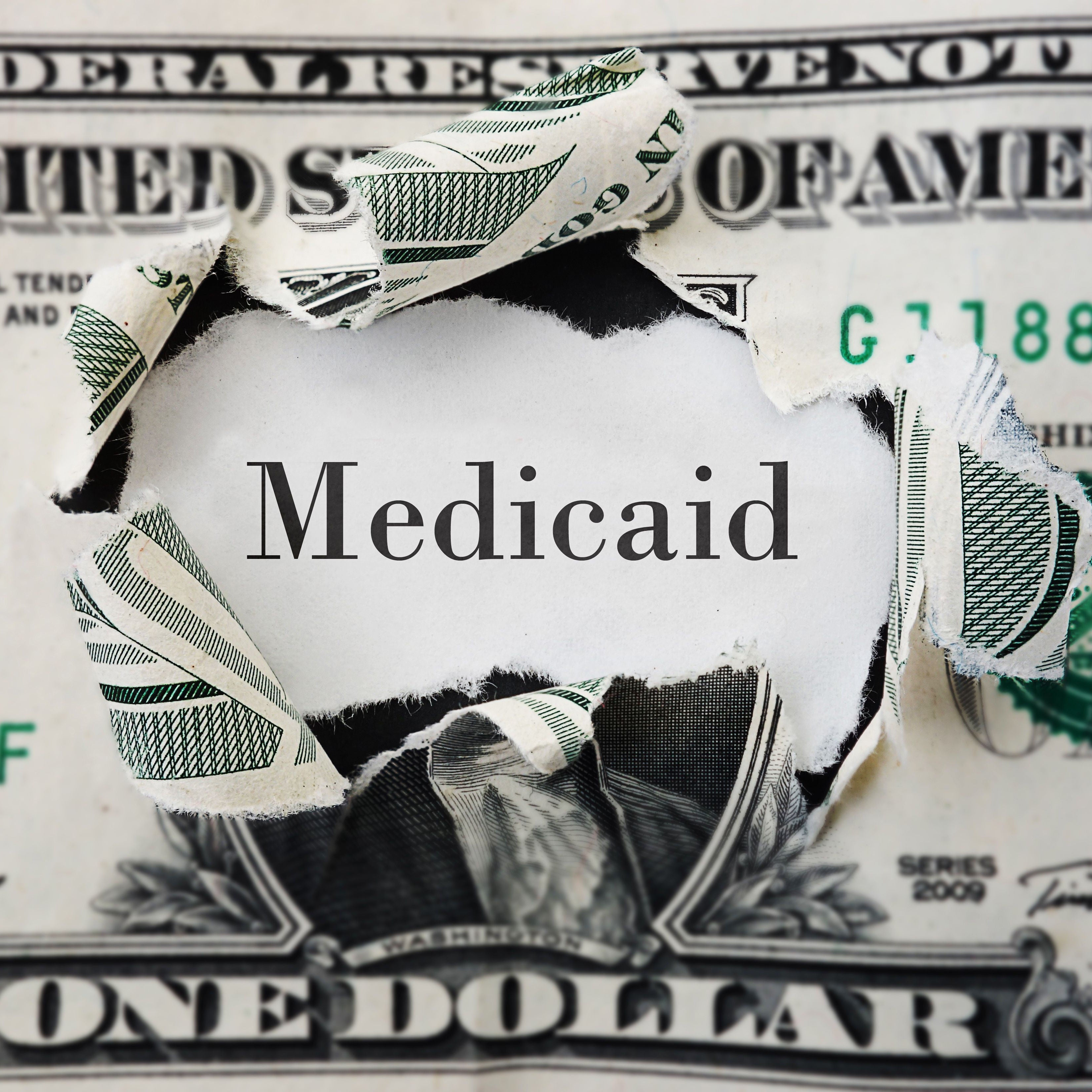 the word medicaid burning through a dollar bill